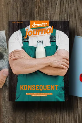 Aktuelles Demeter Journal zeigt einen Landwirt, der die Hände vor einer Milchflasche vor der Brust verschränkt