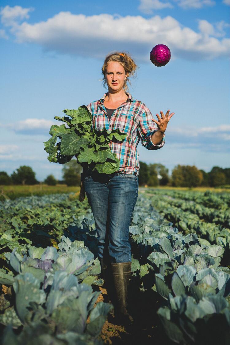 Frau auf Feld wirft Kohl in die Luft