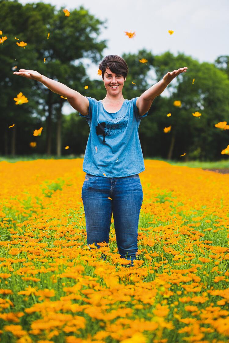 Frau wirft Blumen auf Ringelblumenfeld