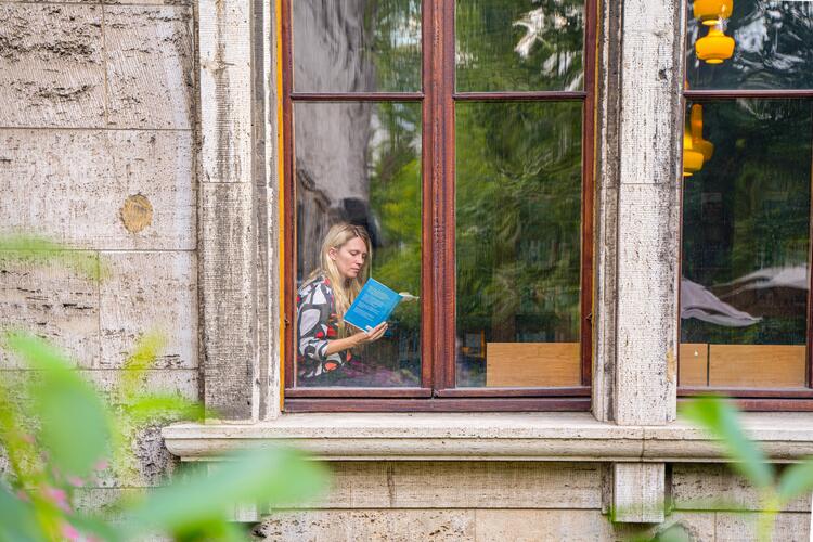 Dr. Kira Vinke ließt am Fenster ein Buch