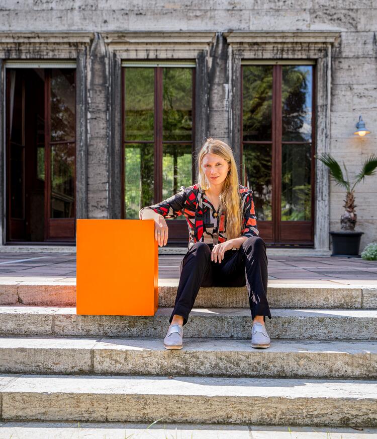 Dr. Kira Vinke mit dem orangen Cube auf einer Treppe