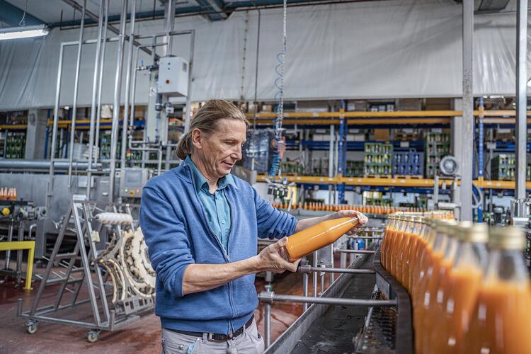 Matthias Maier betrachtet eine Flasche Saft