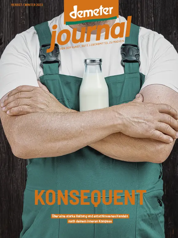 Cover des Demeter Journals zeigt einen Landwirt mit verschränkten Armen vor einer Milchflasche